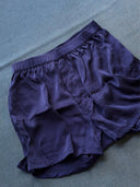 Rimmba | Sustainable Clothing's His & Hers Silk Bottoms - Boxers in navy blue, featuring an elastic waistband, are displayed flat on a textured blue surface to highlight their sustainable zero waste design.
