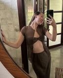 Karunia Fischer's taking a mirror selfie indoors. She wearing Silkchiffon Alila Blouse Ironmud with a small front cut-out and matching skirt. Her hand is resting against a wal, giving a relaxed and confident pose.