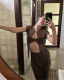 Karunia Fischer's taking a mirror selfie indoors. She wearing Silkchiffon Alila Blouse Ironmud with a small front cut-out and matching skirt. Her hand is resting against a wal, giving a relaxed and confident pose.