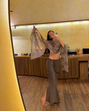Karunia Fischer's posing for a mirror selfie in a warm, modern indoor setting. She is wearing a Mulberry silk aman bias skirt mud with a stylish silkchiffon ecoprint scarf grey draped elegantly around her shoulders and arms.