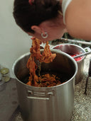 At the Botanical Dye Lingerie Workshop by Rimmba | Sustainable Clothing, a person lifts orange-dyed fabric from a large metal pot, while another pot of red liquid sits nearby—showcasing the process of crafting unique lingerie sets.