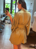 A woman wearing the Bunga Kimono in Mint Green by Rimmba | Sustainable Clothing takes a mirror selfie in a sewing studio, with sewing machines and a dress form in the background.