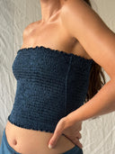A woman models the Indigo Silk Dayu - Elastic Bandeau Top by Rimmba | Sustainable Clothing, posing with her hand on her hip against a light background.
