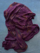 The Eco-Print Silk Chiffon Scarf - Magenta Purple by Rimmba | Sustainable Clothing, featuring sheer silk and botanical prints, is displayed on a textured gray surface.