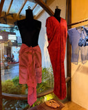 Two mannequins displayed near a window. the left mannequin is wearing ecoprint scarf pink as a skirt. And the right mannequin is wearing Gaya silk kaftan red ecoprint.