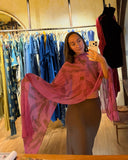 Karunia Fischer's  taking a mirror selfie in RIMMBA boutique. She is weraing Ecoprint scarf pink paired with fitted gray skirt. she is holding a smartphone in one hand while slightly posing, extending her sleeve to show its shape and fabric.