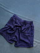 A pair of His & Hers Silk Bottoms - Boxers by Rimmba | Sustainable Clothing, in dark blue natural-dye silk, lies crumpled on a matching blue fabric background.