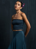 Close-up of woman wearing Mulberry silk midi wrap skirt indigo and strapless top botanical dyed against a dark background.