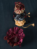 Three Rimmba's jewellery pouch mix colors are stacked on the dark floor and another one is open with a pair of small hoop earrings inside.