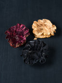 Three Rimmba's jewellery pouch are lined up and open on the dark floor. One of them with a pair of silver small hoop earrings and another one with gold ring.