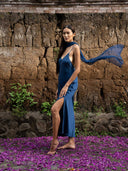 Barefoot woman with long dark hair wearing Mulberry silk midi dress indigo with thin straps and high slit. Flowing silk chiffon scraf indigo handcrafted botanical-dyed sustainable luxury fashion for wedding and resort wear.
