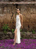 Side-view of woman wearing Mulberry silk halter maxi dress white. Hancrafted botanical-dyed maxi dress sustainable luxury fashion for bridal and resort wear.