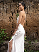 Close-up woman wearing halter neck Mulberry silk dress white.  hancrafted botanical-dyed maxi dress sustainable luxury fashion for bridal and resort wear.