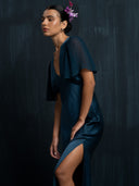 Close up view of woman wearing Mulberry silk dress with V-neckline and flowy silkchiffon sleeves against a dark background.