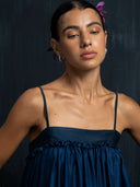 Close-up of indigo silk maxy dress with thin straps and gathered bust detail. Luxury fashion for bridal, formal, and resort wear.