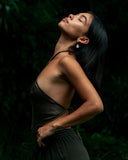 a woman standing with dark long hair wearring Pevita halter top Mud-dye with matching pants. Her face looking up with yard background.