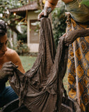 A close up of two woman working together with a piece of cloth covered in a thick, wet mud.