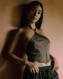 A Woman standing wearing Mulberry Silk crop top Mud-dye Colour and matching pants against a brown background.