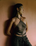 A woman standing wearring Mulberry Silk Halter top mud-dye and matching pants.  handcrafted sustainable luxury fashion for bridal, formal, and resort wear.