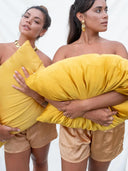 Two women pose with large yellow Pua Silk Pillow Case 2x - Set by Rimmba | Sustainable Clothing against a plain white background; one faces forward, while the other looks to the side.