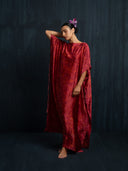 Relaxed pose in red eco-dyed mulberry silk kaftan, handcrafted botanical-dyed maxi dress with wide drape silhouette, sustainable luxury fashion for formal, resort, and evening occasions.
