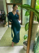 A woman in a Rimmba Ria Silk Dress - Indigo takes a mirror selfie in a bright, plant-filled room with a green rug and large framed mirror, creating a botanical-inspired scene.