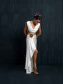 woman wearing a white silk linen blouse cowl neckline and white silk sarong wich is styled slit in the front to showed her knee against a dark background.