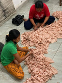 Two women sit on the tiled floor, carefully folding and tying hand-dyed silk for the Scarlette Silk Dress - Pink Circle Motif by Rimmba | Sustainable Clothing.