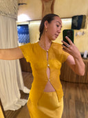 Karunia Fischer's standing a mirror selfie wearing silkchiffon marigold blouse and silksatin marigold skirt. A handmade natural dye Mulberry silk.