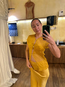 Karunia Fischer's standing mirror selfie wearing yellow blouse and yellow skirt against boutique display backgrund.
