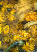 a close-up view of yellow flowers submerged in water. The petals appear soft, crumpled, and densely packed, creating a rich yellow texture throughout the frame
