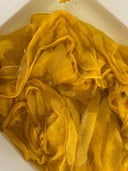 A close up view of yellow silkchiffon scarf submerged in water.
