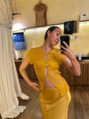Karunia Fischer's standing a mirror selfie wearing silkchiffon marigold blouse and silksatin marigold skirt. A handmade natural dye Mulberry silk.