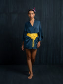 Barefoot woman wearing an indigo silk kimono above the knee and yellow silk belt. Luxury fashion for bridal, daily, and resort wear.