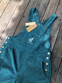 Zion Cotton Corduroy Overalls - Green Natural Dye by Rimmba | Sustainable Clothing, featuring gold buttons, white floral embroidered logo, and brand tags, displayed flat on a wooden surface.